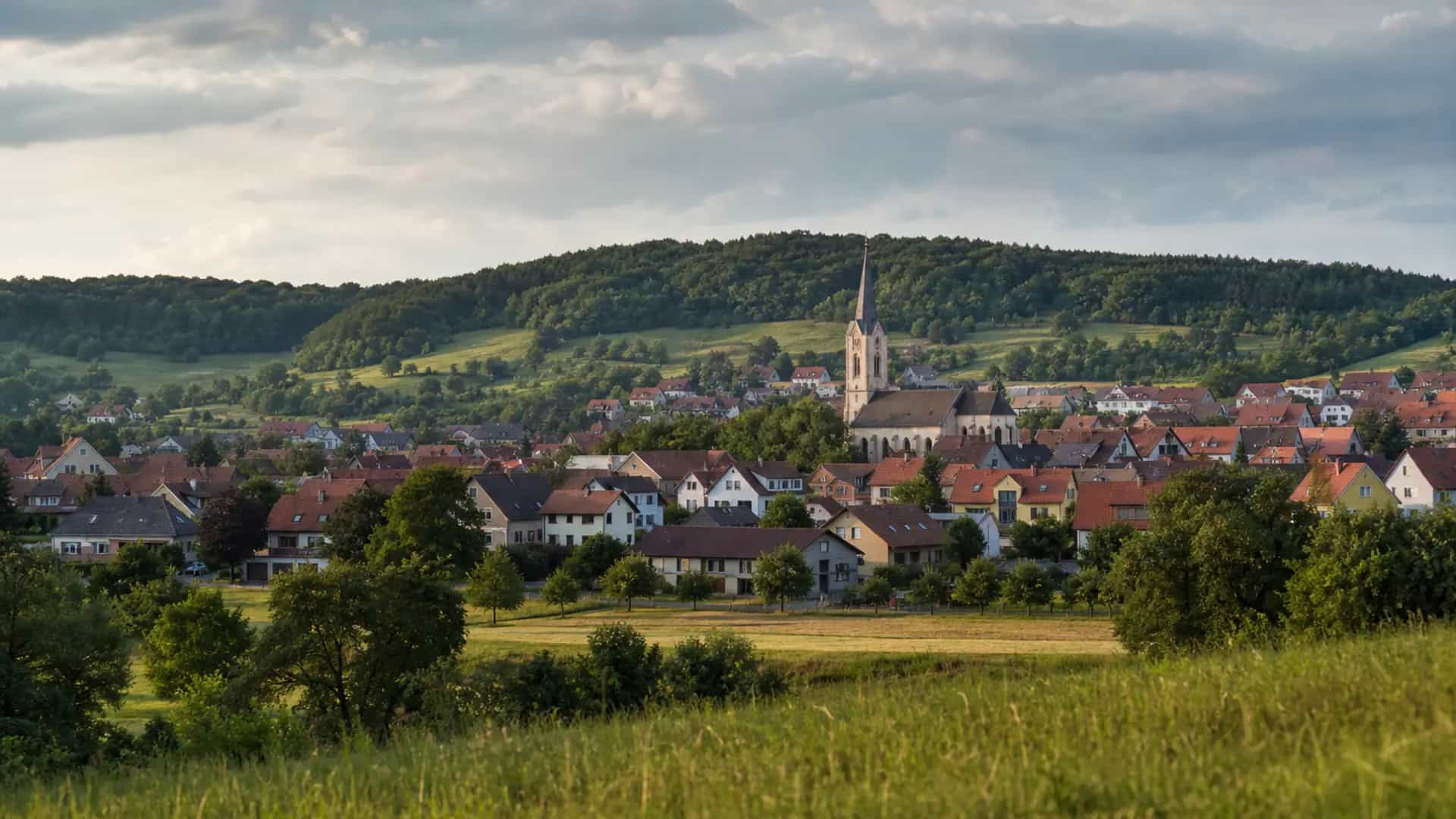 Oberasbach mit Kirche, Dächern und grünen Hügeln bei Tageslicht